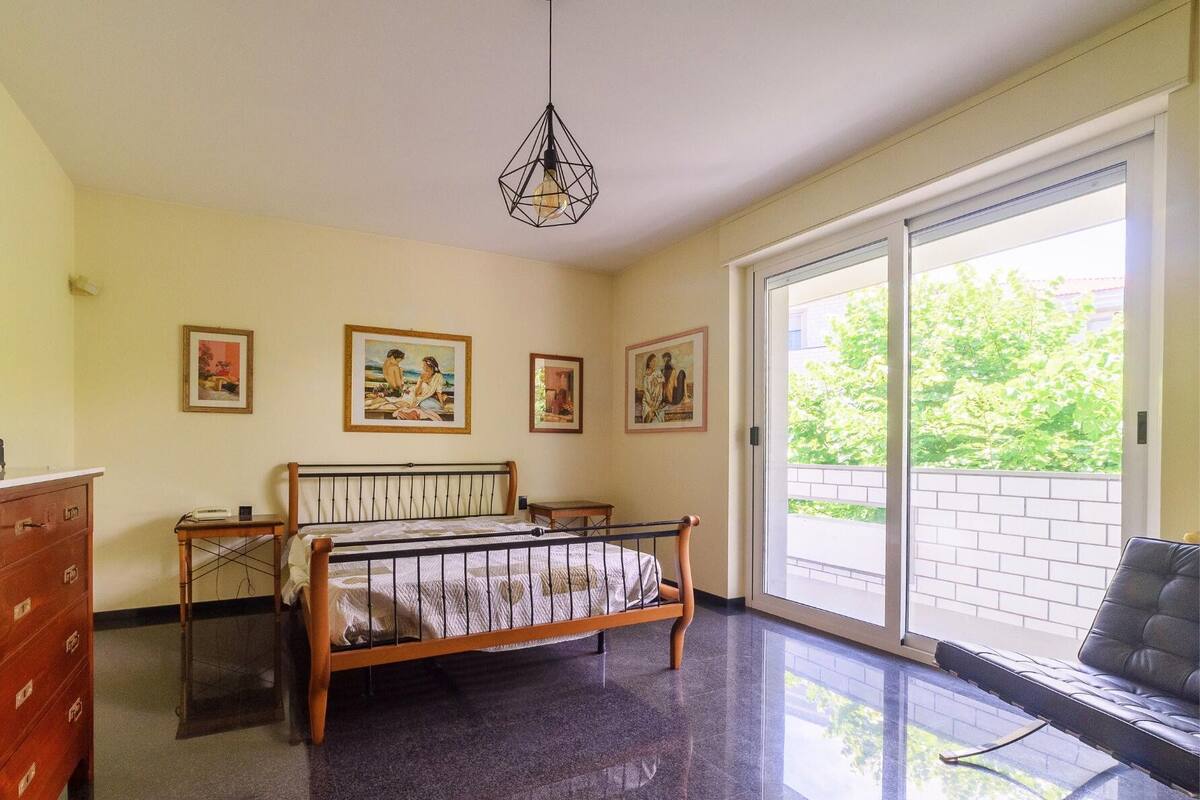 Un dormitorio con una cama, un aparador de madera, un escritorio y una silla. Hay tres cuadros enmarcados en la pared.