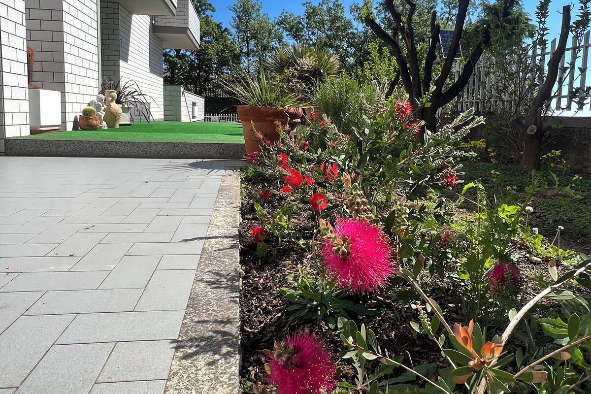 Un edificio moderno con un camino pavimentado y un jardín lleno de flores rosadas.