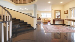A spacious foyer with a curved staircase, a large mirror, and a plush area with a rug. - VILLA PESCARA (Pescara)