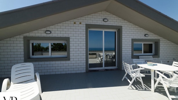 A rooftop terrace with a view of the sea, featuring a table and chairs, and a sliding glass door. - VILLA PESCARA (Pescara)