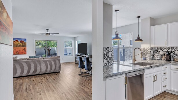 Een moderne keuken met witte kasten, een vaatwasser en een zwart-wit betegelde achterwand.