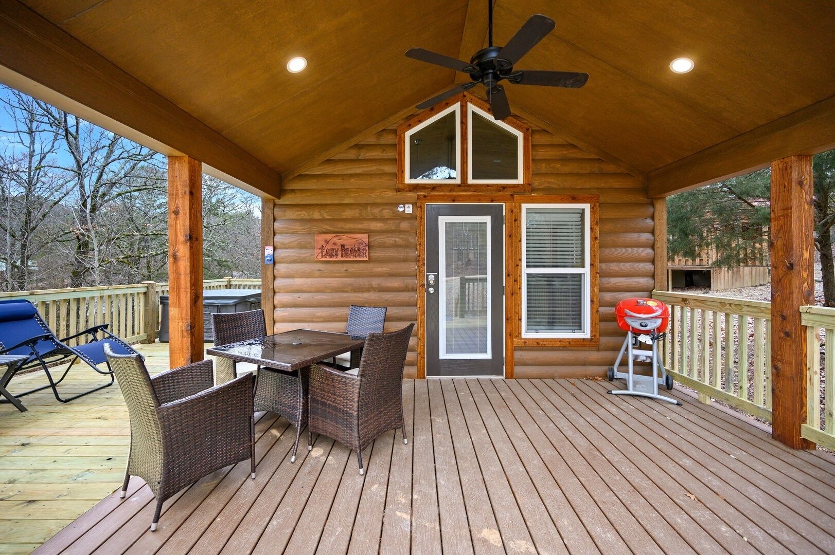 A covered deck with a table and chairs, a ceiling fan, and a barbecue grill.