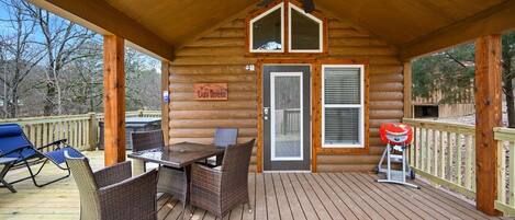 A covered deck with a table and chairs, a ceiling fan, and a barbecue grill.