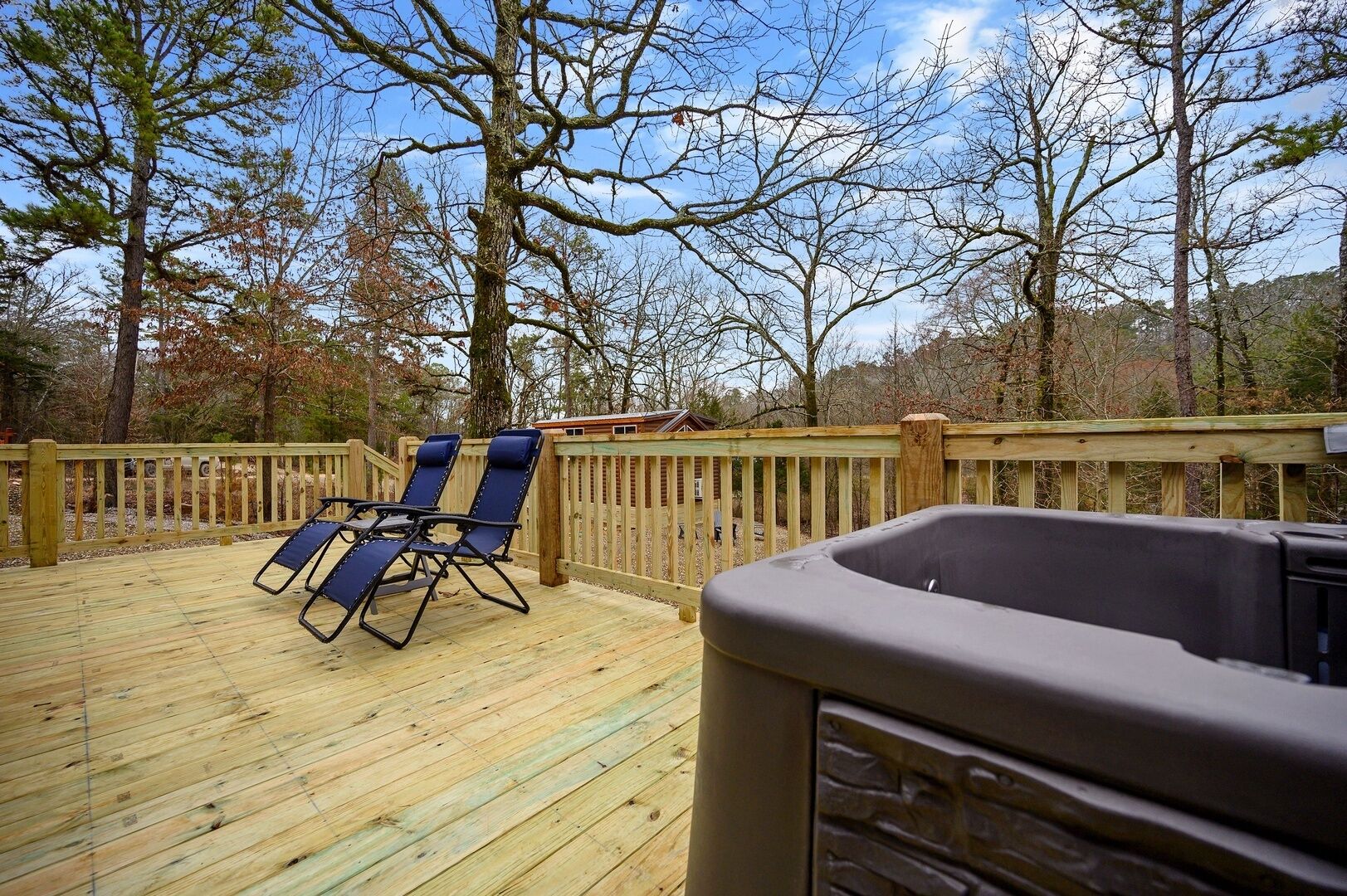 Terraza de madera con dos sillones de descanso y un jacuzzi.