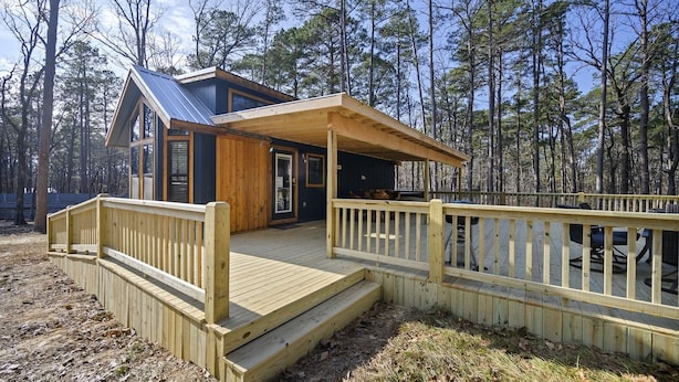 A cabin with a wooden deck, a covered porch, and a large window.