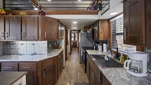 A spacious kitchen with wooden cabinets, granite countertops, and a stainless steel sink.