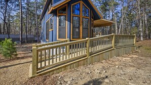 A cabin with a wooden deck and a fenced area.