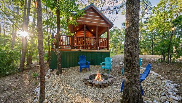 A cabin with a wooden deck, a fire pit, and blue chairs.