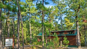 A cabin in a forest with a sign indicating it's a SkyRun vacation rental.