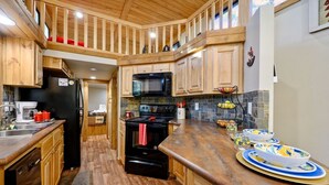 A kitchen with wooden cabinets, a black refrigerator, a microwave, and a stove.