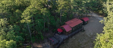 A cabin with a red roof, surrounded by dense forest.