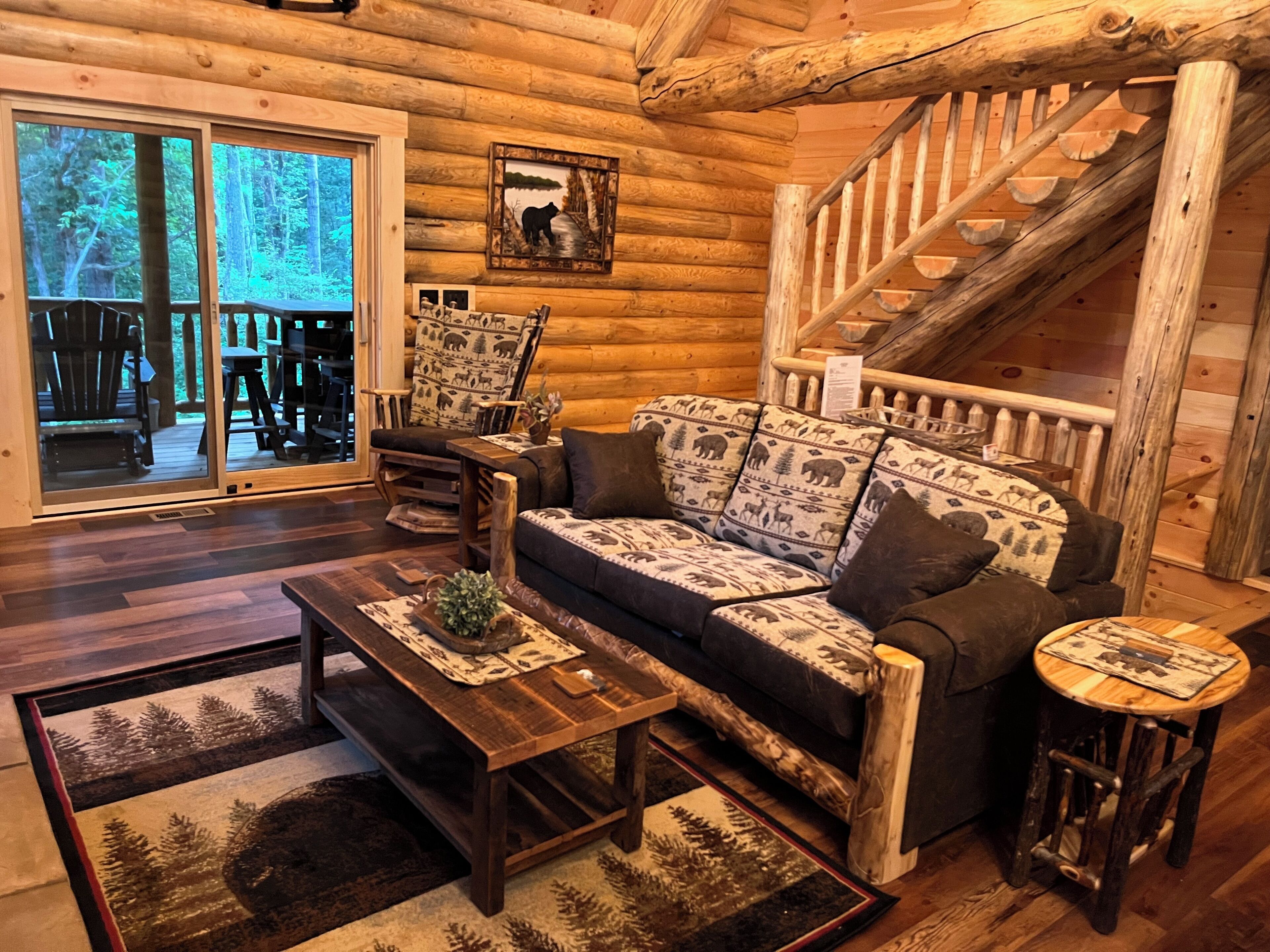 A log cabin interior with a sofa, coffee table, and a staircase.