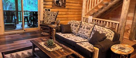 A log cabin interior with a sofa, coffee table, and a staircase.