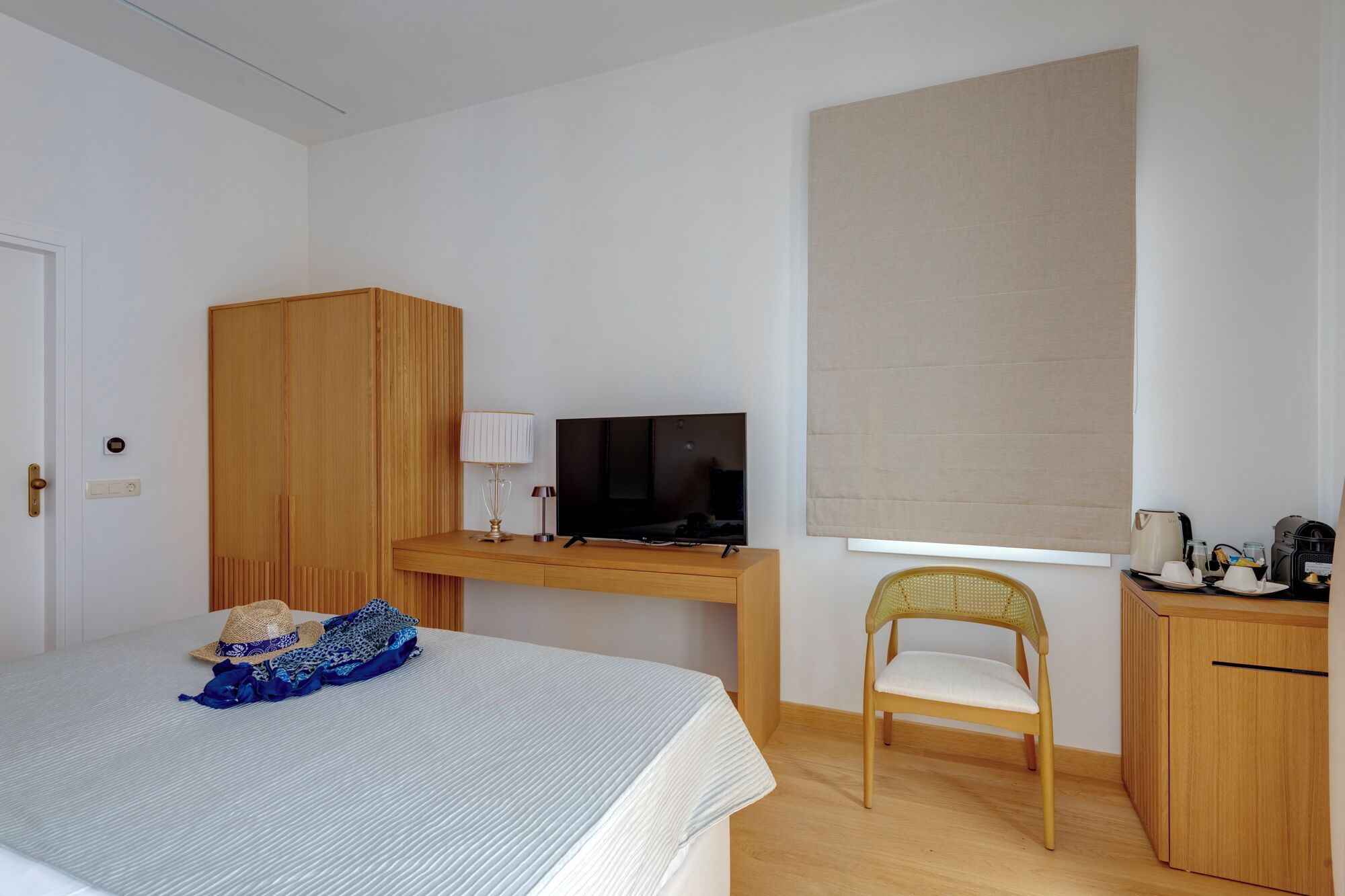 Un dormitorio con cama, escritorio con televisor, silla y armario.