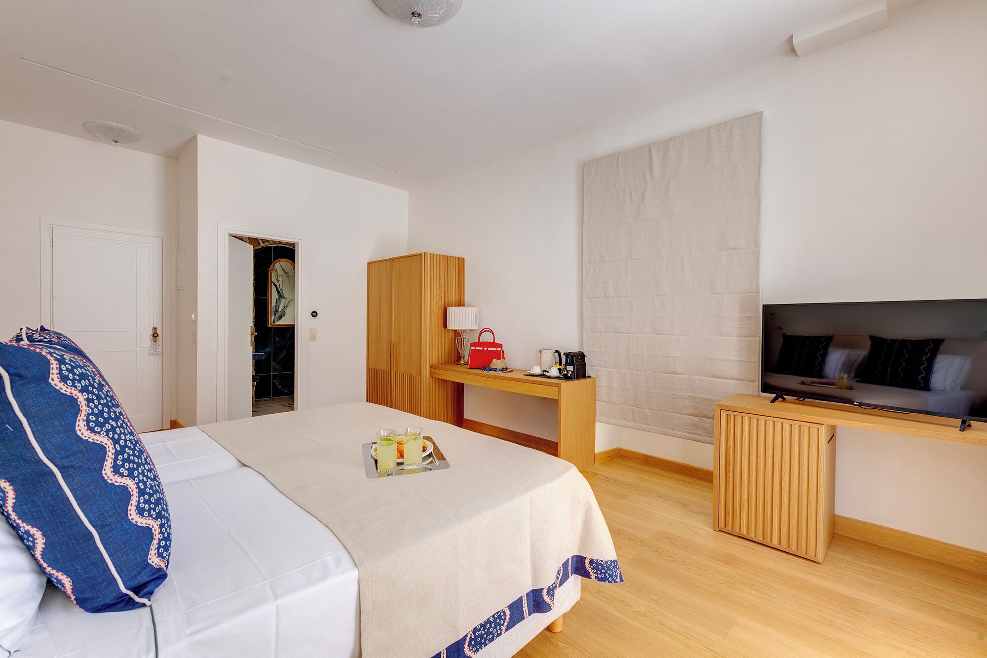 A hotel room with a bed, a desk, a TV, and a wardrobe.