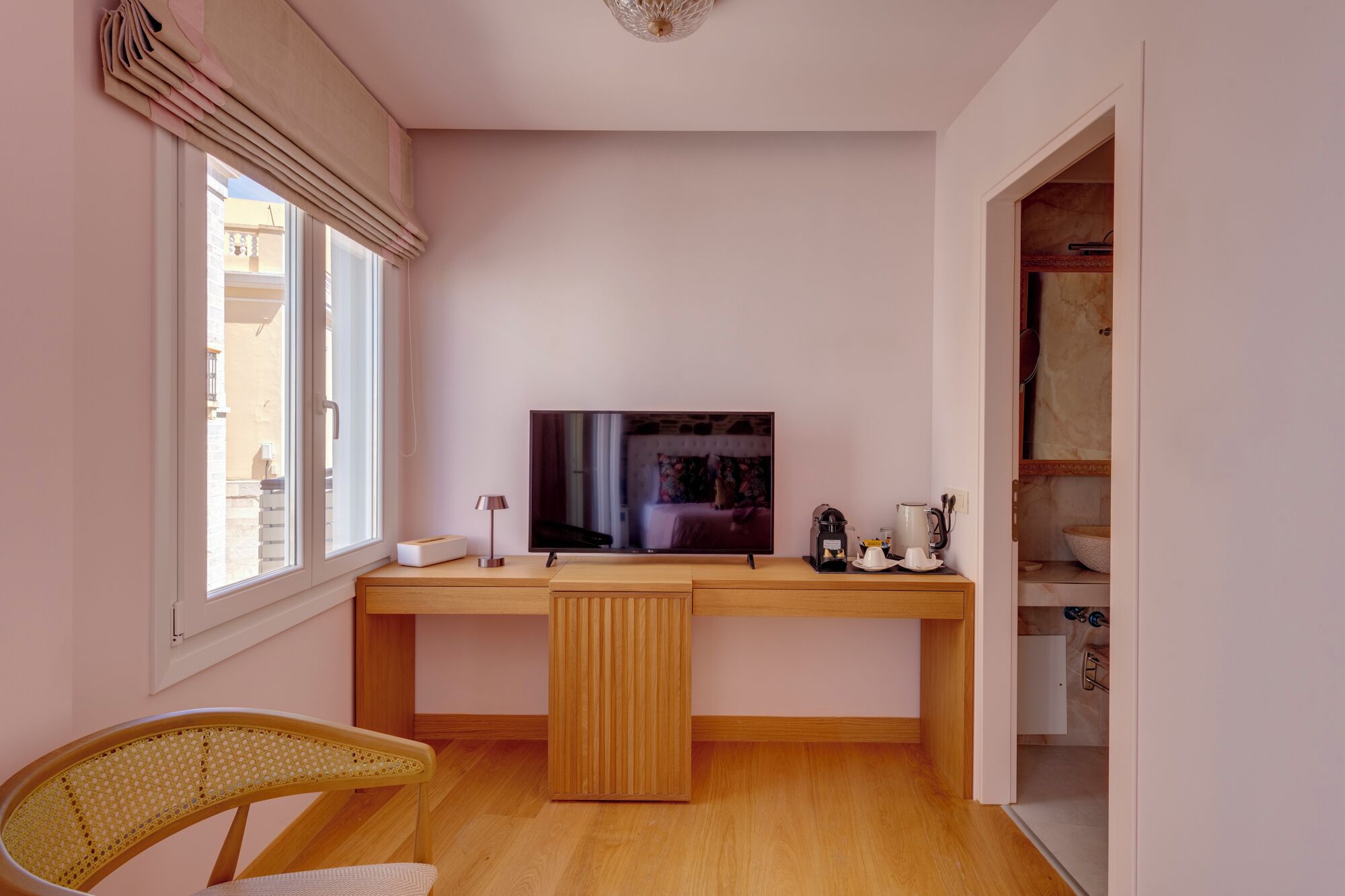 A compact room with a wooden desk, a television, a chair, and a wardrobe.