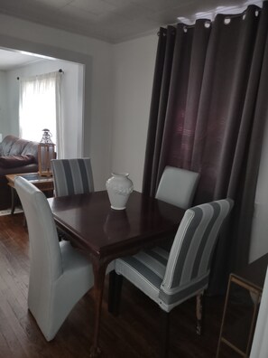 Una zona pranzo con un tavolo in legno, sedie a righe e un vaso bianco.