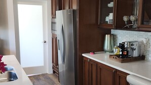 A kitchen with wooden cabinets, a stainless steel refrigerator, a coffee machine, and a sink.