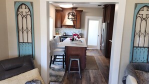 A compact kitchen with a central island, wooden cabinets, and a hanging light fixture.