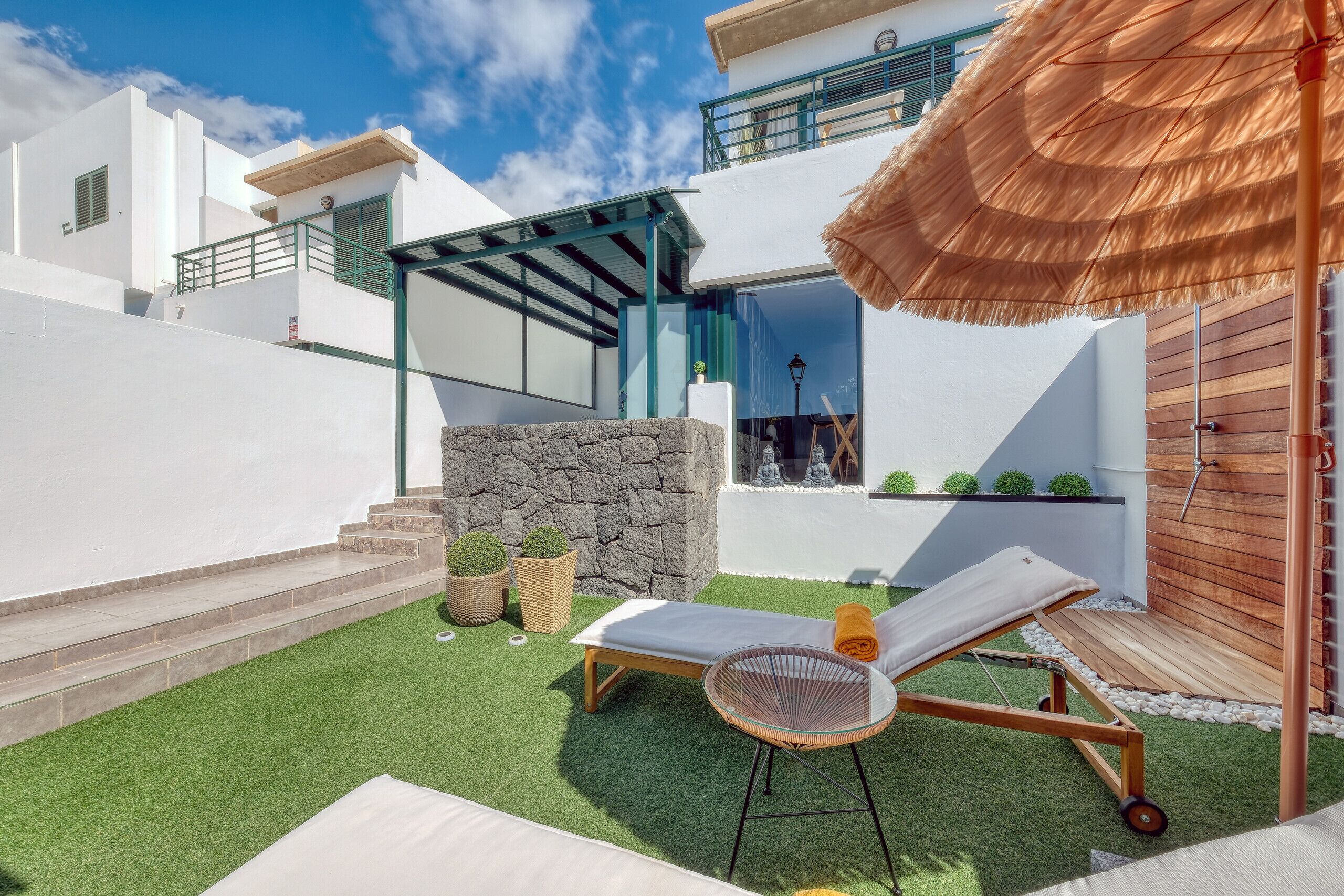 Een modern buitengebied met een loungestoel, een tafeltje en een rieten parasol.