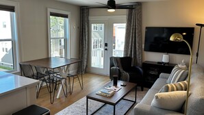 En moderne stue med spiseområde, sofa, sofabord og fjernsyn.