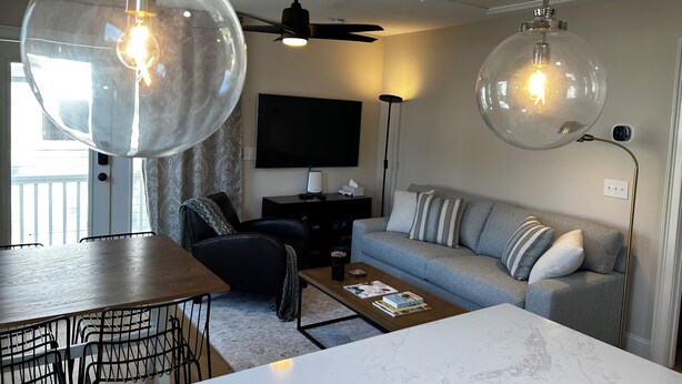 En moderne stue med spiseplads, der indeholder en sofa, sofabord og et fjernsyn.