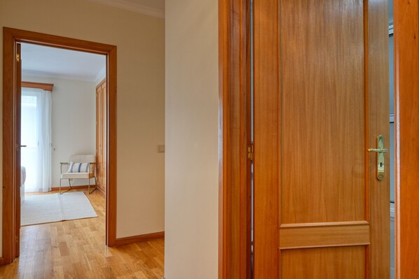 A hallway with a wooden door and a white chair in the background. - Costa do Sol, a Home in Madeira (Funchal)