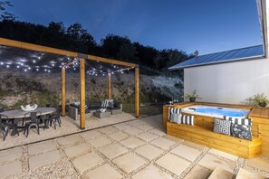 Patio esterno con vasca idromassaggio, zona relax e luci decorative.