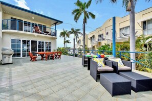 A rooftop patio with outdoor furniture, a barbecue grill, and a pool table.