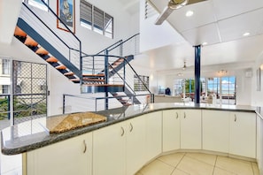 Enjoy a spacious kitchen with a curved countertop, white cabinetry, and a large window offering a view of the outdoors.