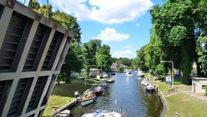 Un canal amb barques amarrades a ambdós costats, un pont per a vianants i un edifici amb façana de rejuntada.