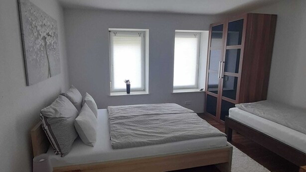Ein Schlafzimmer mit einem Bett, Nachttisch, Lampe und Kleiderschrank.