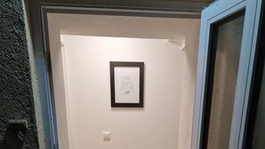 Ein Durchgang zu einem Raum mit einem gerahmten Zitat an der Wand, einem kleinen Teppich und einem Lüftungsgitter auf dem Boden.