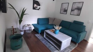 Ein modernes Wohnzimmer mit einem türkisfarbenen Sofa, einem Couchtisch und einem Blumentopf.