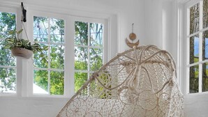 A room with a large, woven hanging chair with a cushion and a bright yellow pillow. - Charming Home and Cottage in Downtown St Augustine for 14 (St. Augustine)