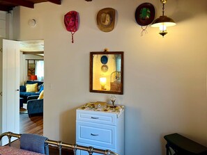 A room with a blue sofa, a white dresser, a mirror, and a ceiling fan.