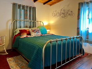 A bedroom with a metal bed frame, teal bedding, and a wall-mounted bicycle decoration.