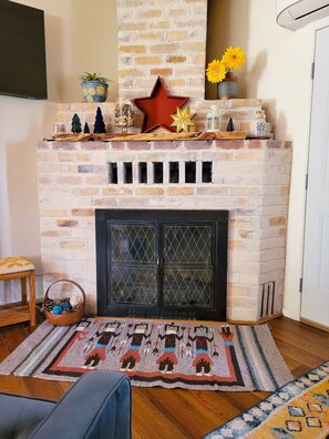 A brick fireplace with decorative items, a rug, and a wooden bench.
