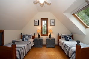 Un dormitorio con dos camas, una ventana y un ventilador de techo.