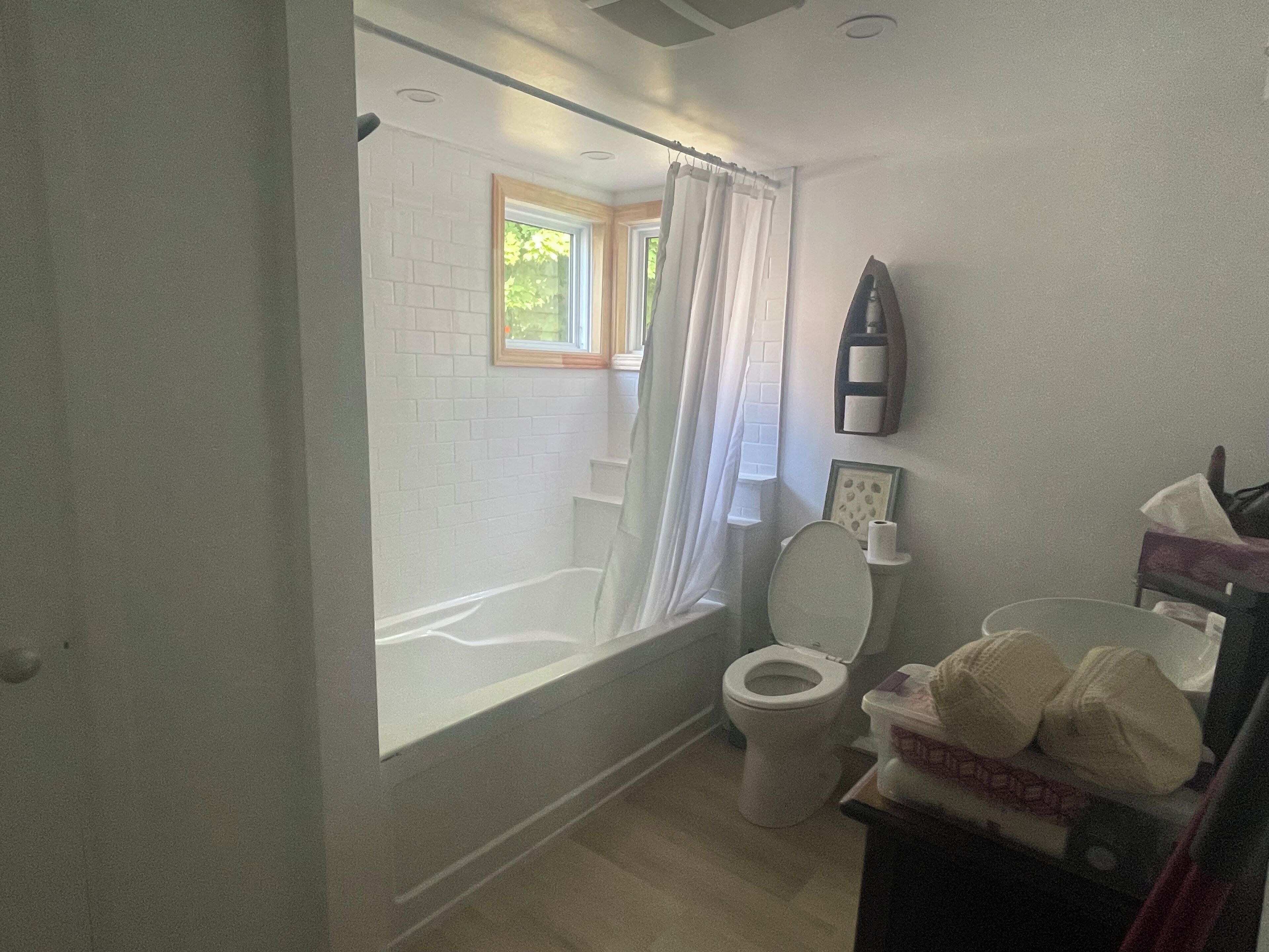 Ein Badezimmer mit Badewanne, Toilette und einem Fenster mit Blick auf Grünflächen.