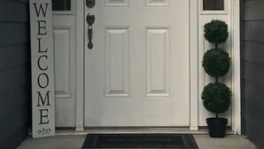 A white front door with a 'WELCOME' sign, a mailbox, and a potted plant. - Beautiful Family Home  (Tallahassee)