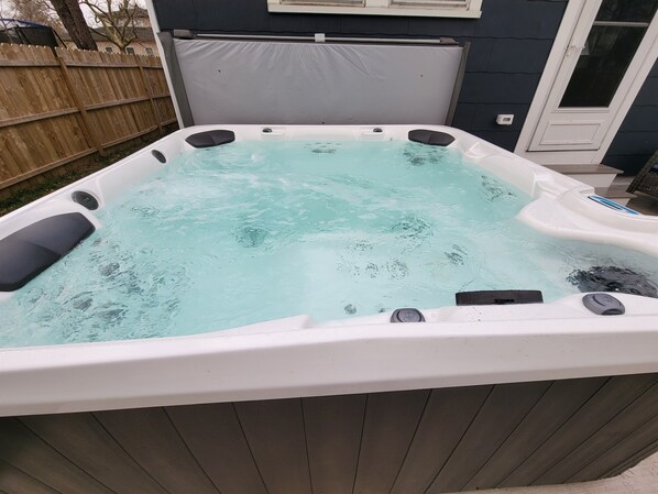 A hot tub with a wooden deck surrounding it.