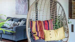 A room with a hanging chair, a sofa, and a wall-mounted artwork. - A family-friendly getaway, with outdoor pool and beautiful view!
(Newmarket)