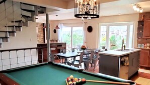 A pool table with balls, a dining area with chairs, a kitchen with cabinets, and a staircase. - A family-friendly getaway, with outdoor pool and beautiful view!
(Newmarket)