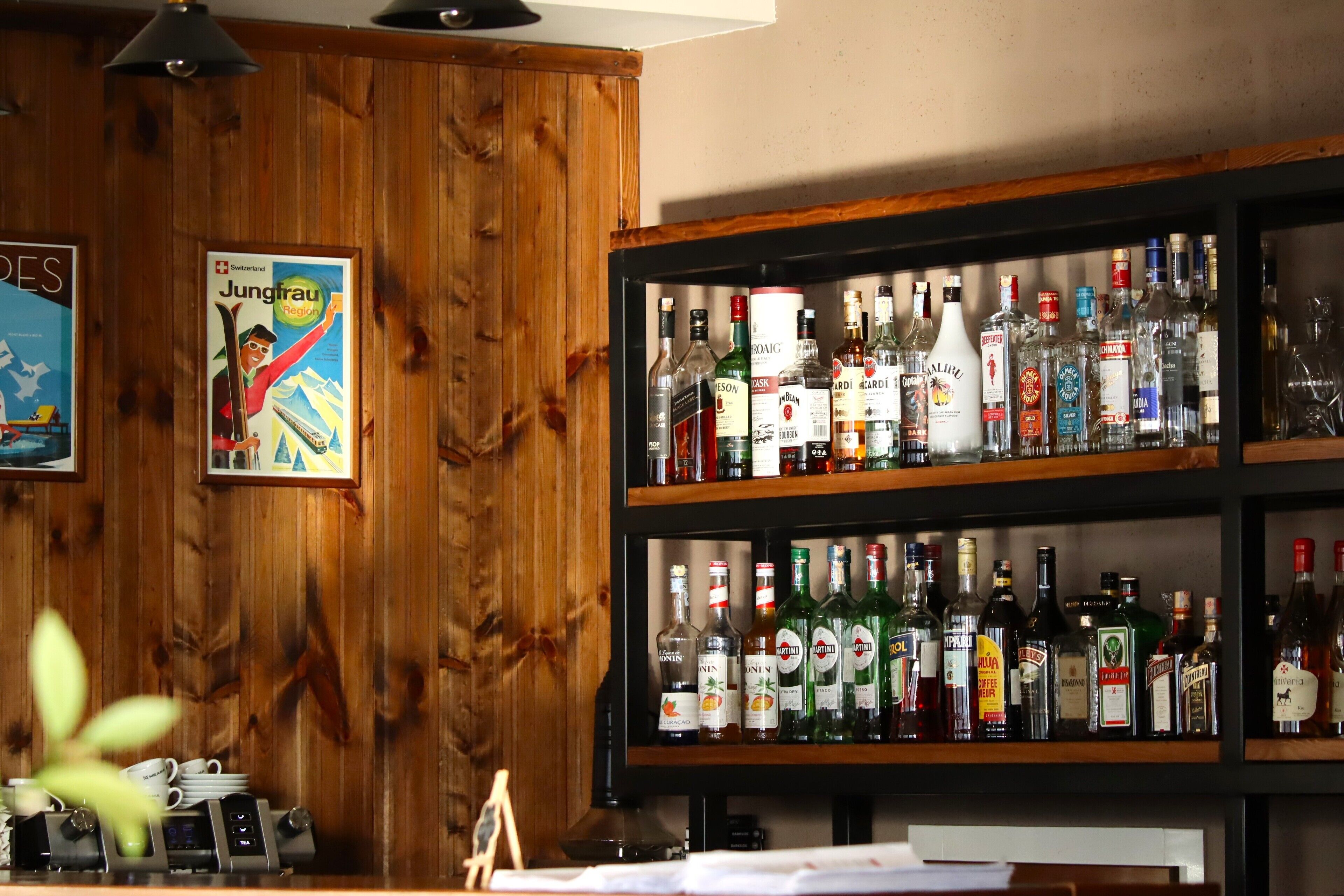 A bar area with wooden walls and shelves stocked with various liquor bottles.