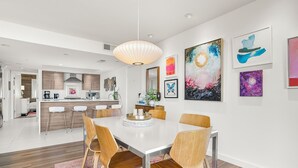 A modern dining area with a white table, wooden chairs, and a central light fixture. - Luxury Condo in the Sky! Finest in Wintergreen! (Wintergreen Resort)