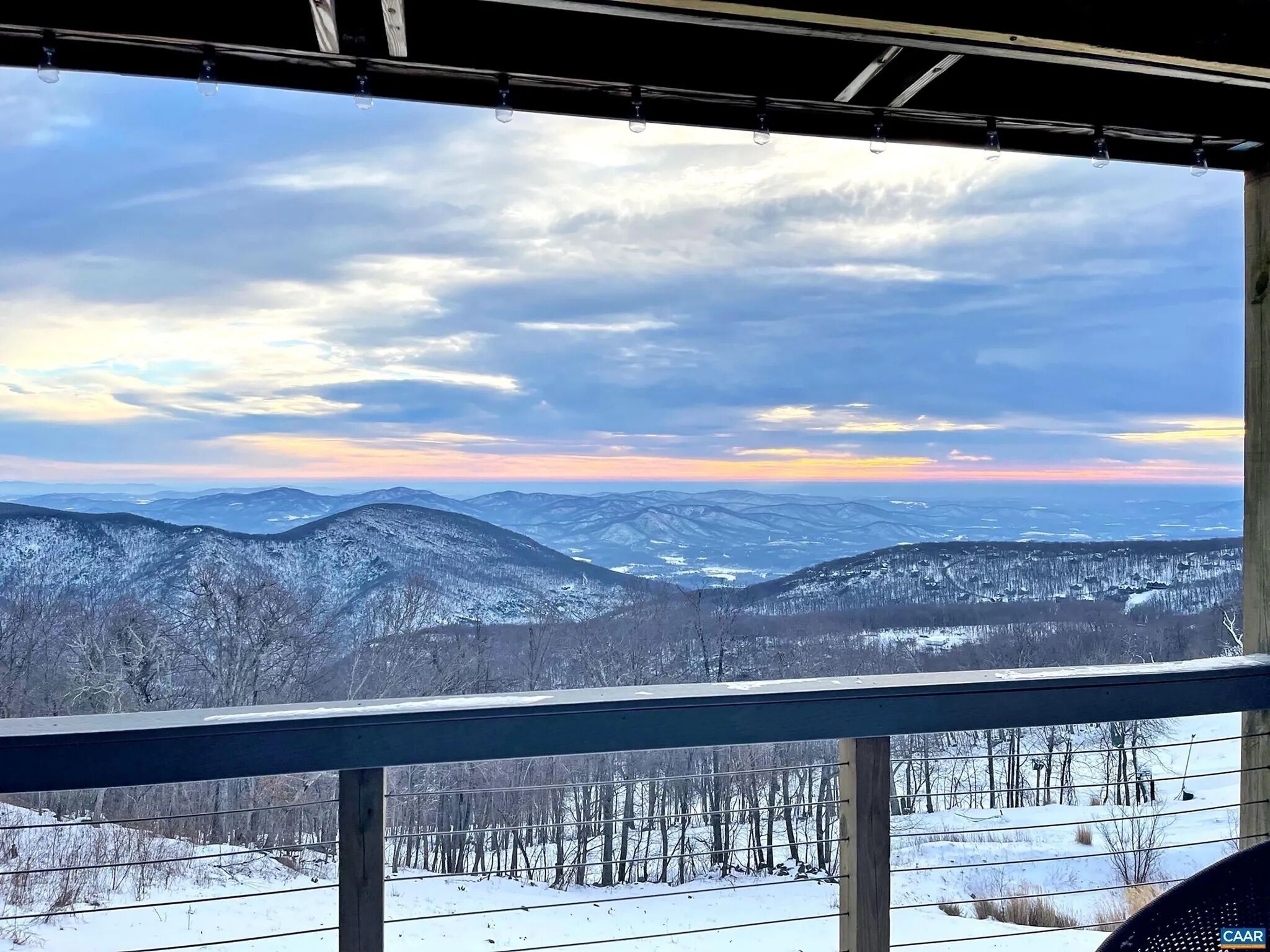 A view from a window overlooking snow-covered mountains and a forested area.