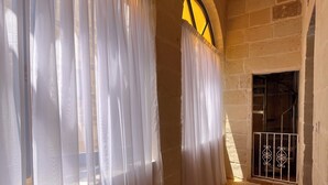 A corridor with white curtains, stone walls, and a metal gate. - House of character with pool & jacuzzi for 5 persons, central yet quiet location (Nadur)