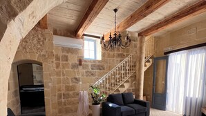A spacious living room with a stone wall, a staircase, a chandelier, and a sofa. - House of character with pool & jacuzzi for 5 persons, central yet quiet location (Nadur)