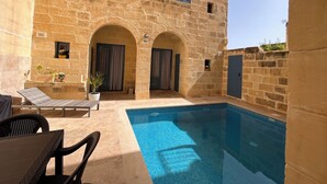 A stone building with a swimming pool, outdoor seating, and potted plants. - House of character with pool & jacuzzi for 5 persons, central yet quiet location (Nadur)